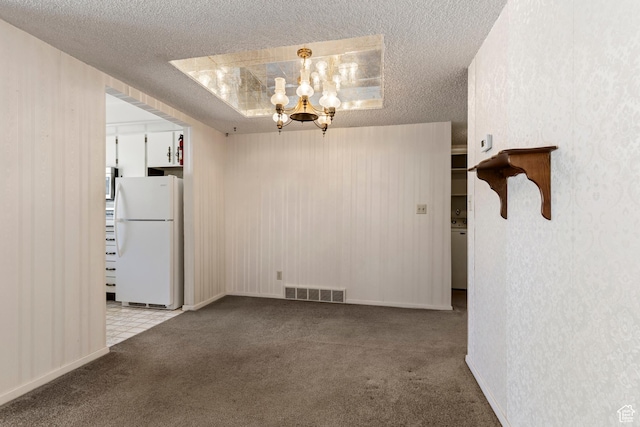 carpeted empty room with visible vents, a notable chandelier, and a textured ceiling