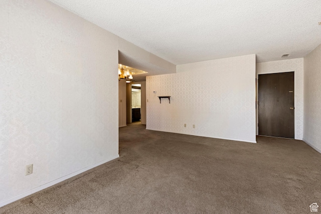 empty room with an inviting chandelier, wallpapered walls, carpet floors, and a textured ceiling