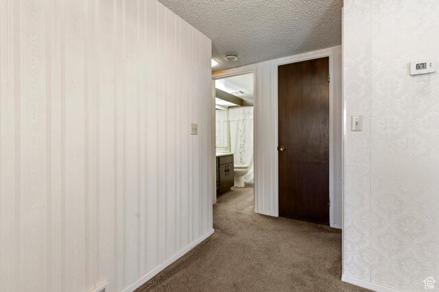 hallway with a textured ceiling and carpet