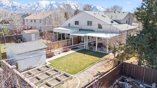 rear view of house with an outdoor structure, a fenced backyard, a storage shed, a vegetable garden, and a lawn