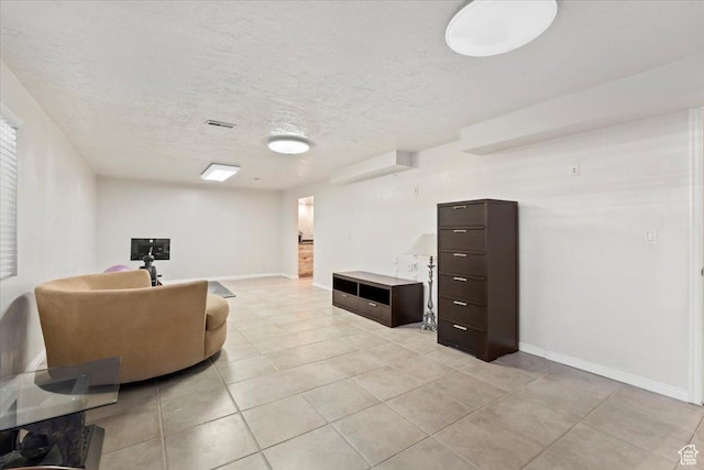 living room with light tile patterned flooring, baseboards, and a textured ceiling