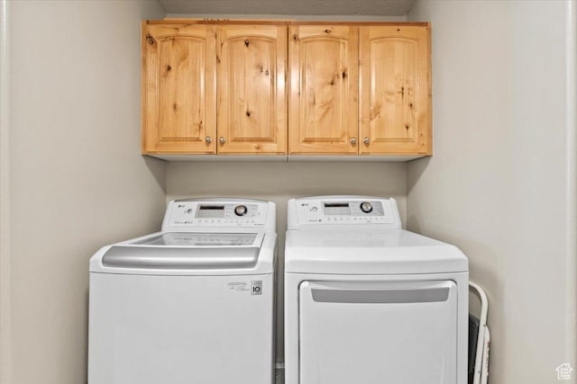 washroom featuring washing machine and clothes dryer and cabinet space