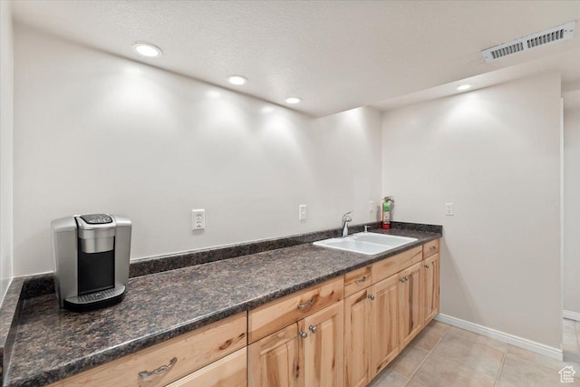 kitchen with recessed lighting, light tile patterned floors, light brown cabinetry, a sink, and visible vents