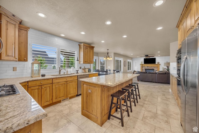 686 Wellington Dr, Kaysville, UT 84037 - kitchen with open floor plan, stainless steel appliances, a center island, a sink, and a fireplace