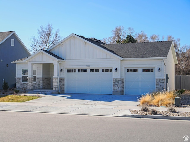 view of front of property with stone siding, an attached garage, board and batten siding, and driveway