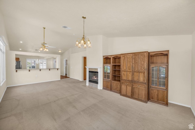 unfurnished living room featuring lofted ceiling, light carpet, ceiling fan, a chandelier, and a tile fireplace