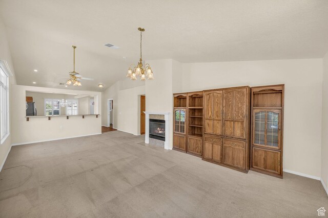 1673 W Warm River Dr, St George, UT 84790 - unfurnished living room with vaulted ceiling, light carpet, ceiling fan, a chandelier, and a tiled fireplace