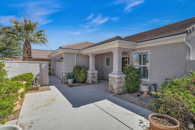 1673 W Warm River Dr, St George, UT 84790 - view of front of property featuring a garage, stucco siding, a tiled roof, and covered porch