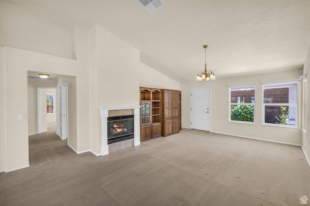 unfurnished living room with light carpet, a tiled fireplace, plenty of natural light, a chandelier, and high vaulted ceiling