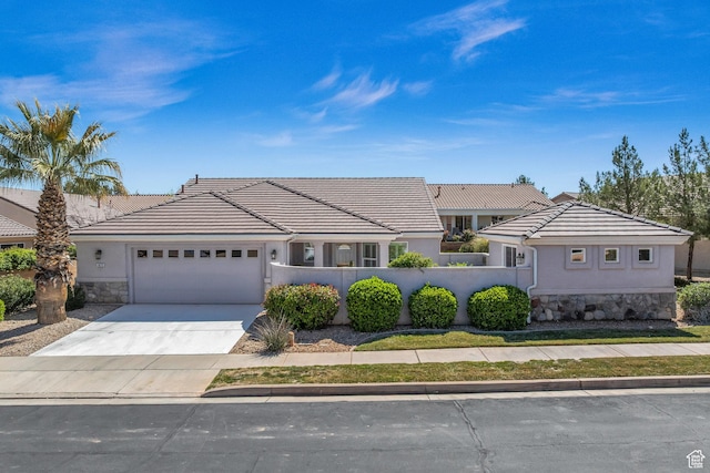 1673 W Warm River Dr, St George, UT 84790 - view of front of home featuring stone siding, a fenced front yard, an attached garage, concrete driveway, and stucco siding