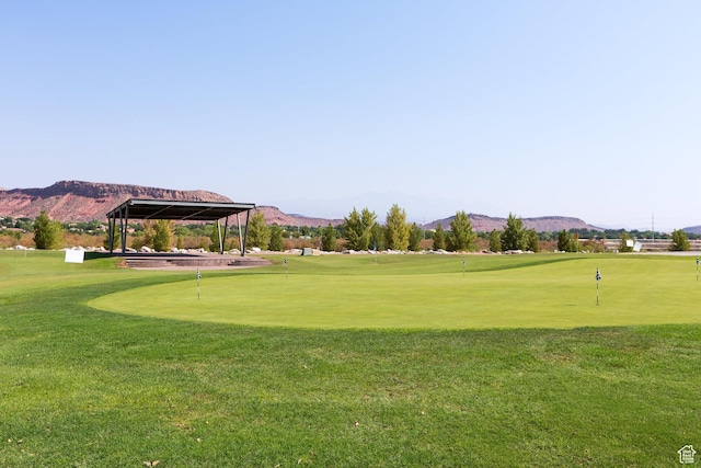 surrounding community featuring a mountain view, a putting area, and golf course view