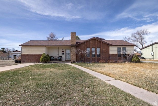 view of front of house featuring brick siding, a chimney, and a front yard