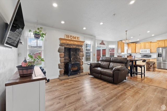 7217 W Mccuiston Ave S, Herriman, UT 84096 - living area featuring lofted ceiling, recessed lighting, a wood stove, a chandelier, and light wood-style floors