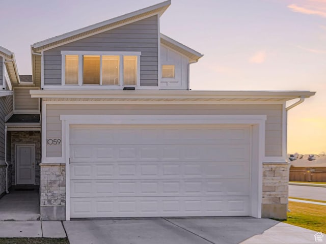 view of front of house with stone siding, a garage, and concrete driveway