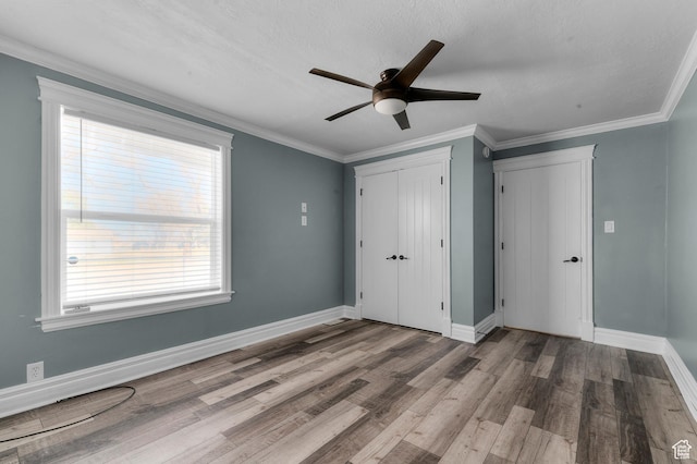 unfurnished bedroom with a closet, crown molding, baseboards, and wood finished floors