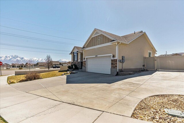 6403 W Muzzle Loader Dr, Herriman, UT 84096 - view of side of home with a mountain view, a gate, concrete driveway, a garage, and board and batten siding