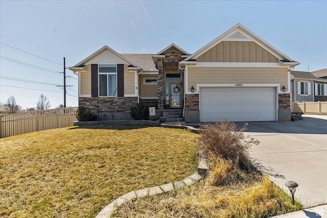 craftsman-style home featuring driveway, stone siding, fence, an attached garage, and a front lawn