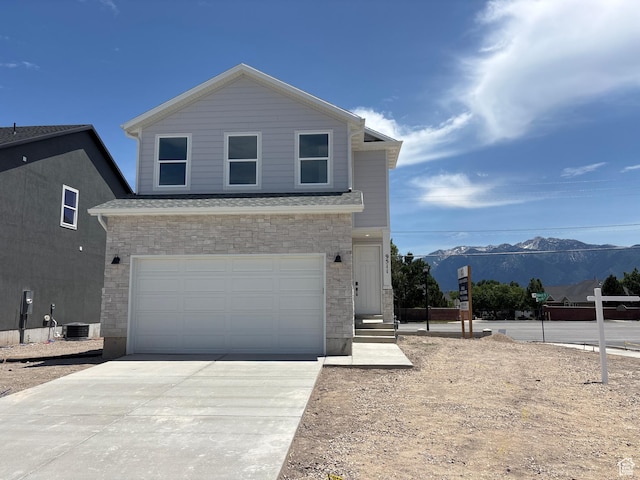 9511 S Tirado Cv W Unit 204, South Jordan, UT 84095 - view of front of property with stone siding, a mountain view, driveway, and a garage