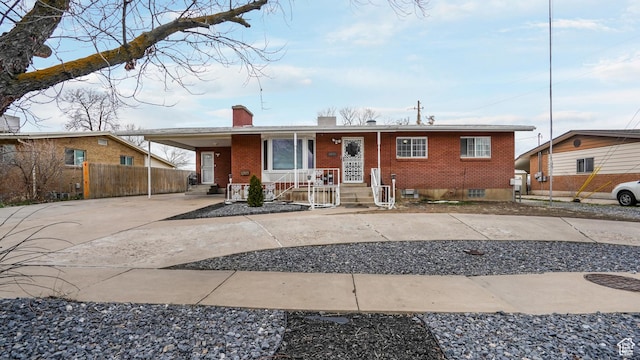 4535 S Ridgeline Dr, Ogden, UT 84405 - view of front of home with covered porch, concrete driveway, an attached carport, a chimney, and brick siding