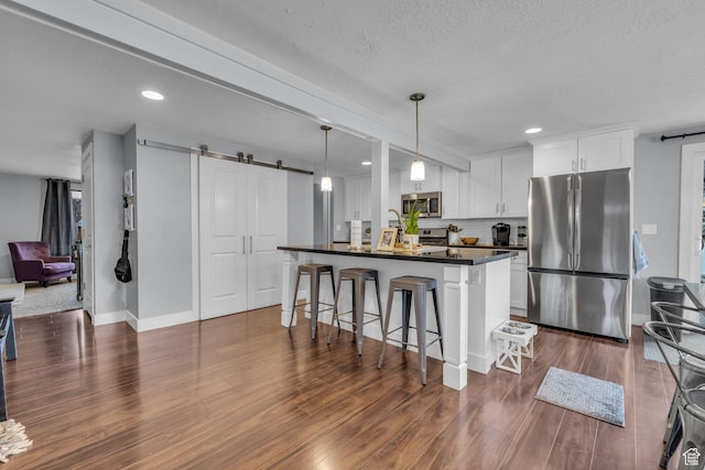 175 E Millerberg Dr S, Sandy, UT 84070 - kitchen featuring white cabinets, stainless steel appliances, dark countertops, a barn door, and a breakfast bar area
