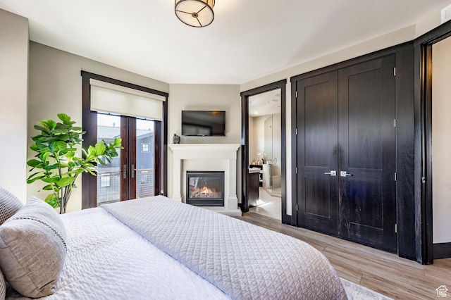 3788 Blackstone Dr Unit 19, Park City, UT 84098 - bedroom with a glass covered fireplace, baseboards, ensuite bathroom, light wood-style floors, and access to exterior