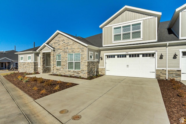 craftsman house with stone siding, board and batten siding, driveway, and an attached garage