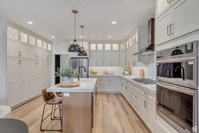 813 S 1260 W Unit 111, Heber City, UT 84032 - kitchen featuring light countertops, light wood-style flooring, stainless steel appliances, wall chimney range hood, and backsplash