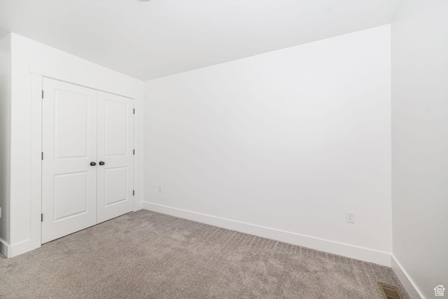 unfurnished bedroom with baseboards, visible vents, a closet, and carpet