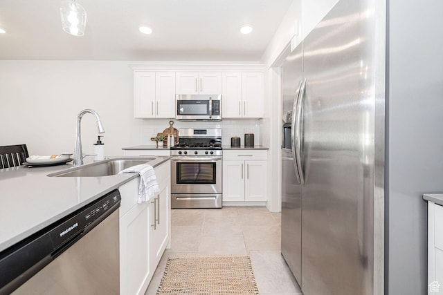 kitchen with light countertops, stainless steel appliances, white cabinetry, a sink, and backsplash