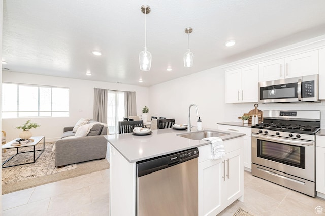 kitchen with light countertops, stainless steel appliances, an island with sink, a sink, and open floor plan