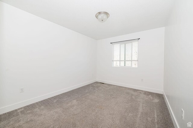 spare room featuring carpet and baseboards