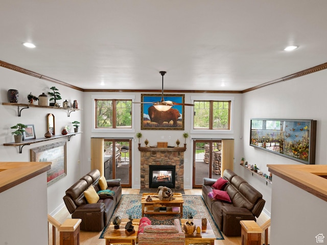 living area featuring baseboards, recessed lighting, ornamental molding, and a stone fireplace