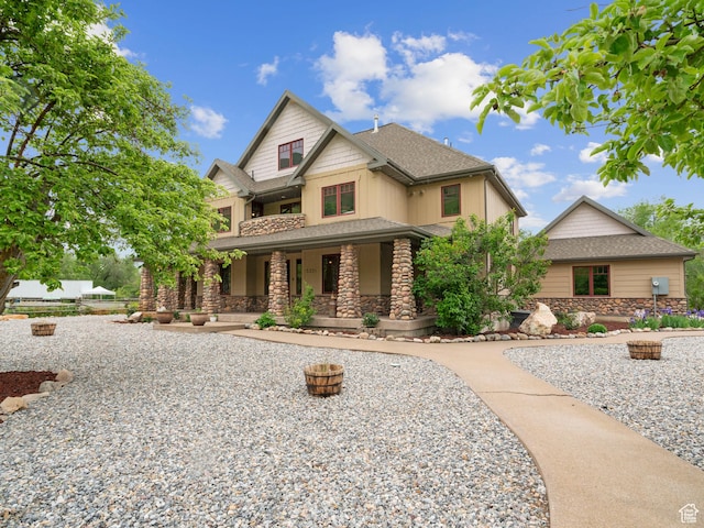 craftsman inspired home featuring a porch, roof with shingles, and stone siding