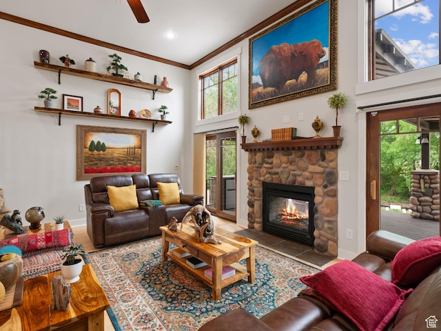 living area with crown molding, baseboards, a fireplace, a ceiling fan, and a high ceiling