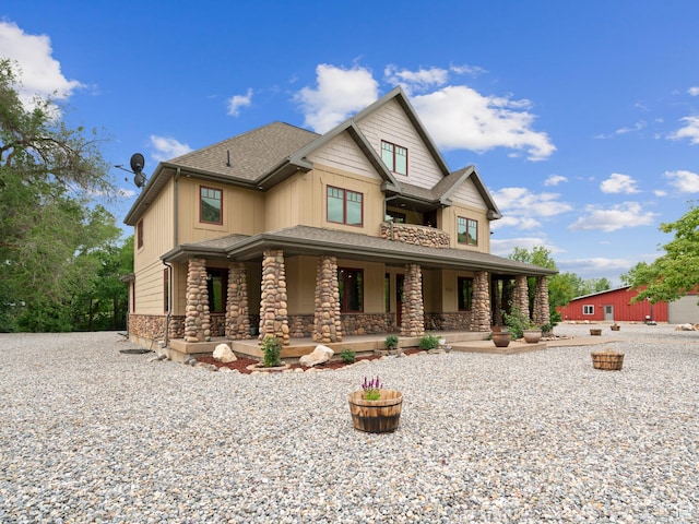 craftsman house featuring roof with shingles, covered porch, board and batten siding, and stone siding