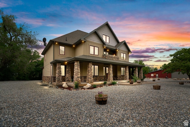 view of front facade featuring covered porch, board and batten siding, and stone siding
