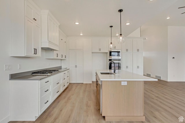 8077 N Bristle Cone Rd, Eagle Mountain, UT 84005 - kitchen with white cabinetry, a sink, light wood finished floors, visible vents, and appliances with stainless steel finishes
