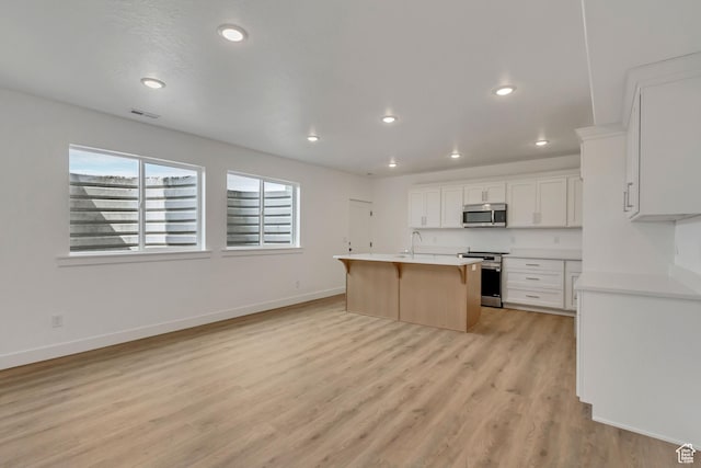 8077 N Bristle Cone Rd, Eagle Mountain, UT 84005 - kitchen with a kitchen breakfast bar, light wood-type flooring, a sink, visible vents, and appliances with stainless steel finishes