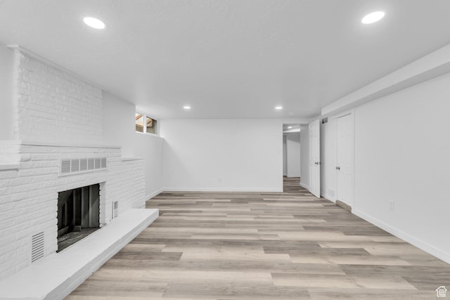 unfurnished living room with visible vents, recessed lighting, a brick fireplace, and wood finished floors