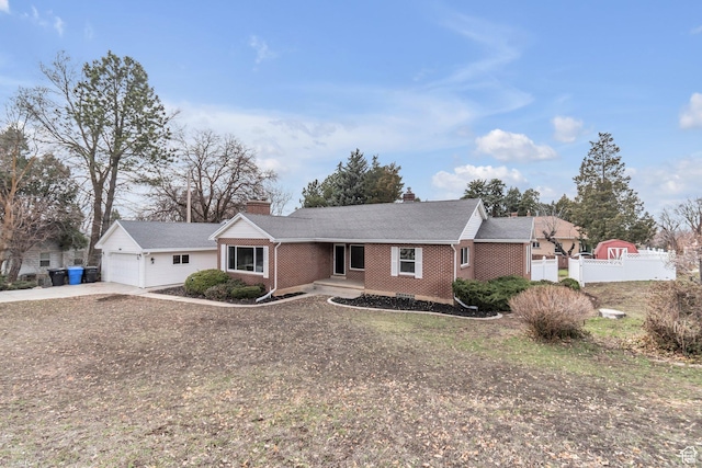 single story home featuring concrete driveway, fence, brick siding, a garage, and a chimney