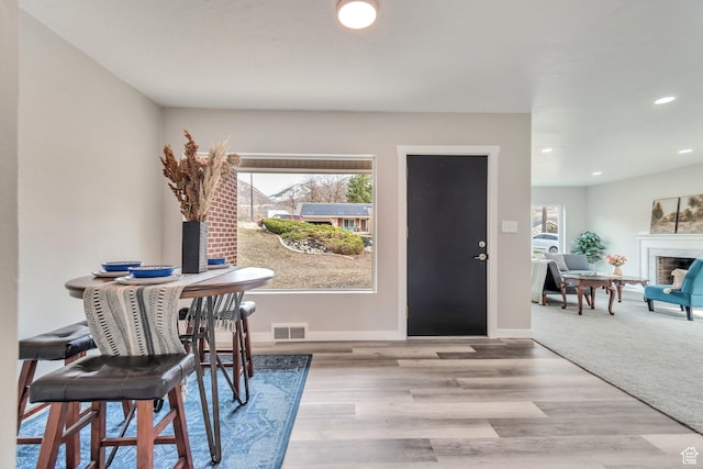 dining area with a fireplace, wood finished floors, baseboards, visible vents, and recessed lighting