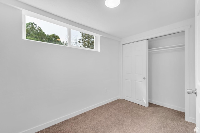 unfurnished bedroom with light carpet, baseboards, and a closet
