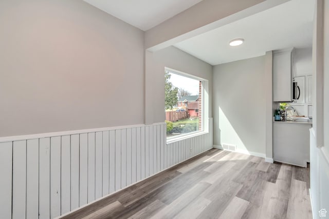 spare room featuring baseboards, visible vents, light wood-style flooring, and a sink