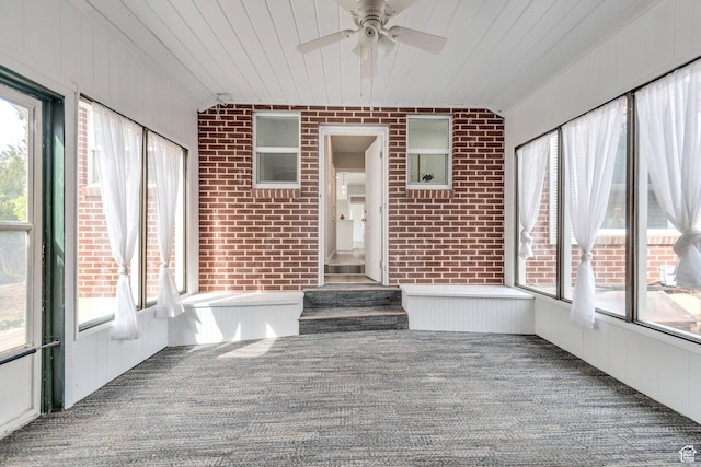 unfurnished sunroom with carpet, wooden ceiling, and brick wall