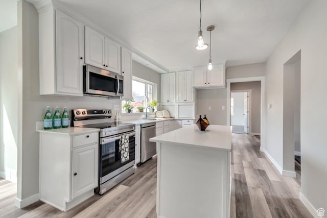 kitchen featuring a sink, appliances with stainless steel finishes, a center island, white cabinets, and light wood-style floors