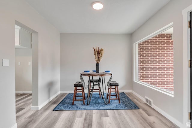 dining area with baseboards, visible vents, and wood finished floors
