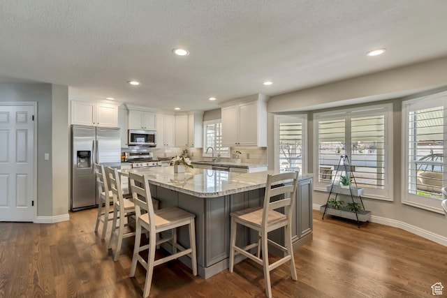 kitchen featuring white cabinets, decorative backsplash, appliances with stainless steel finishes, and light stone counters