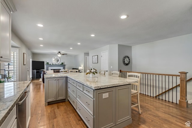 kitchen featuring a breakfast bar, gray cabinetry, light wood-style flooring, and open floor plan