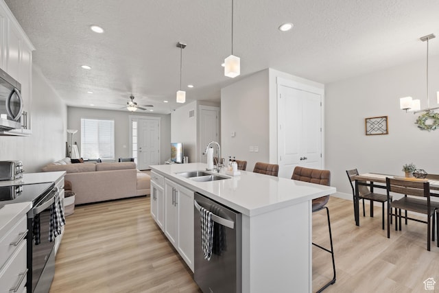 kitchen featuring a textured ceiling, a kitchen breakfast bar, a sink, and stainless steel appliances