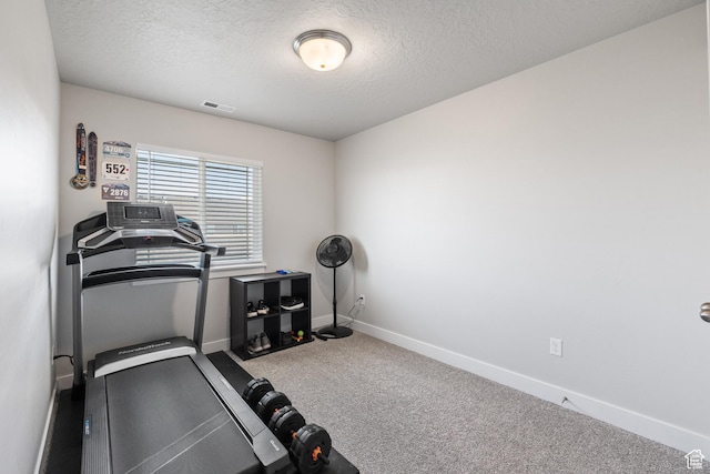 exercise room featuring carpet, baseboards, a textured ceiling, and visible vents